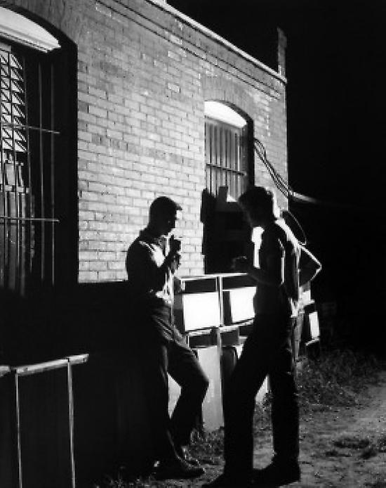 Two men smoking cigarettes outside building Poster