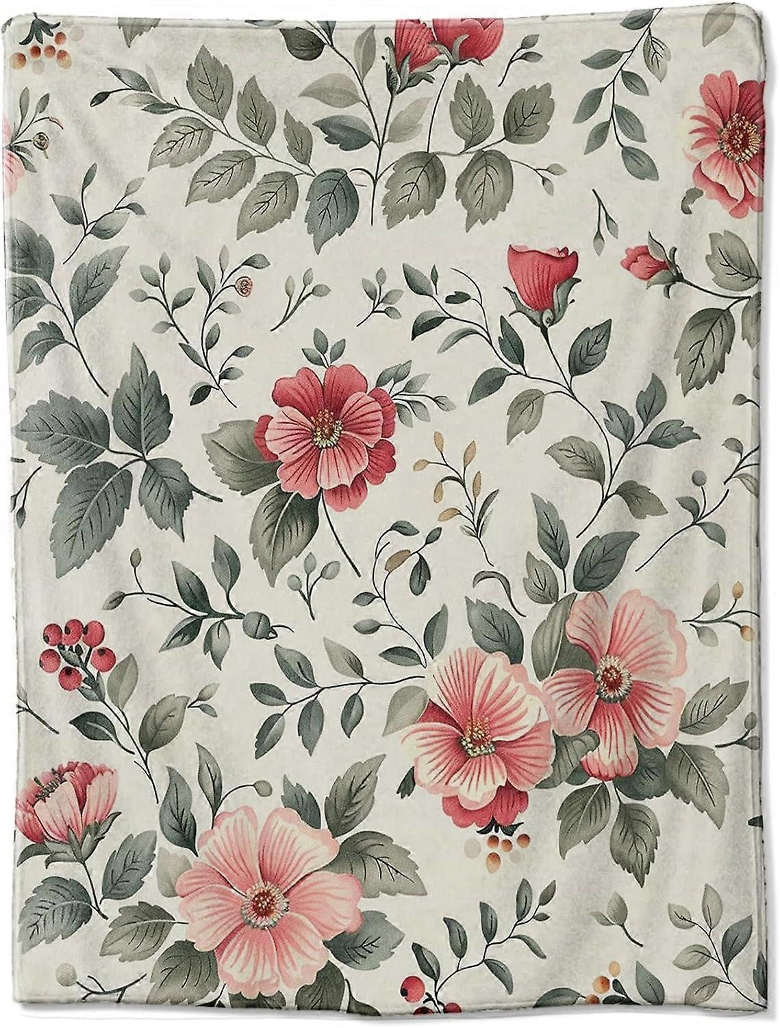 La coperta di flanella Vintage flower charm, su uno sfondo crema, è  intervallata da vivaci fiori rossi e rosa e foglie verdi evocano c