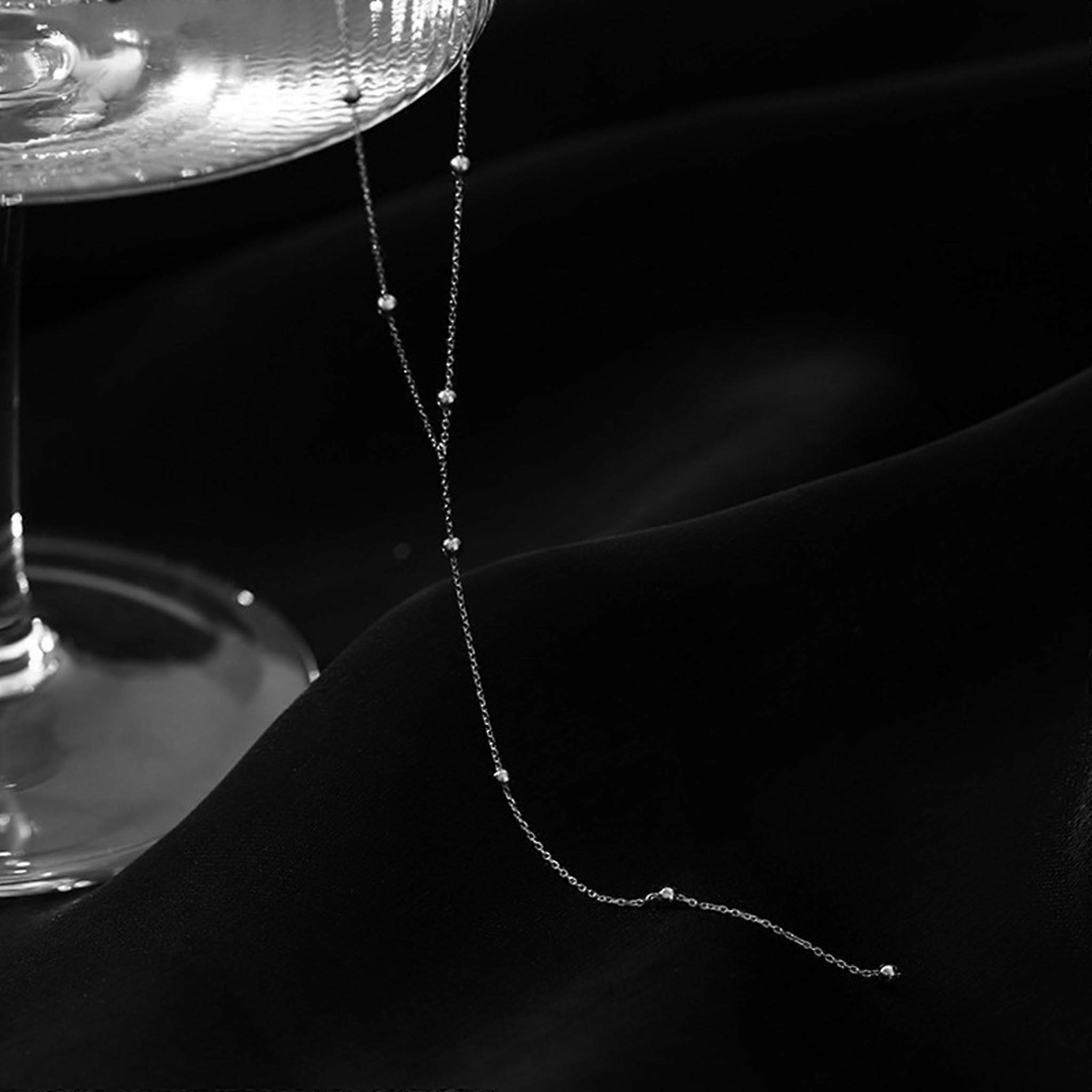 Silvertoned women's round pearl necklace with long tassel, deep neckline, and collarbone chain.