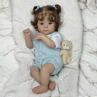 Reborn pop met zacht stoffen lichaam – krullend haar, met een jumpsuit outfit.
